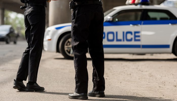 cropped shot of police officers standing in front of police car